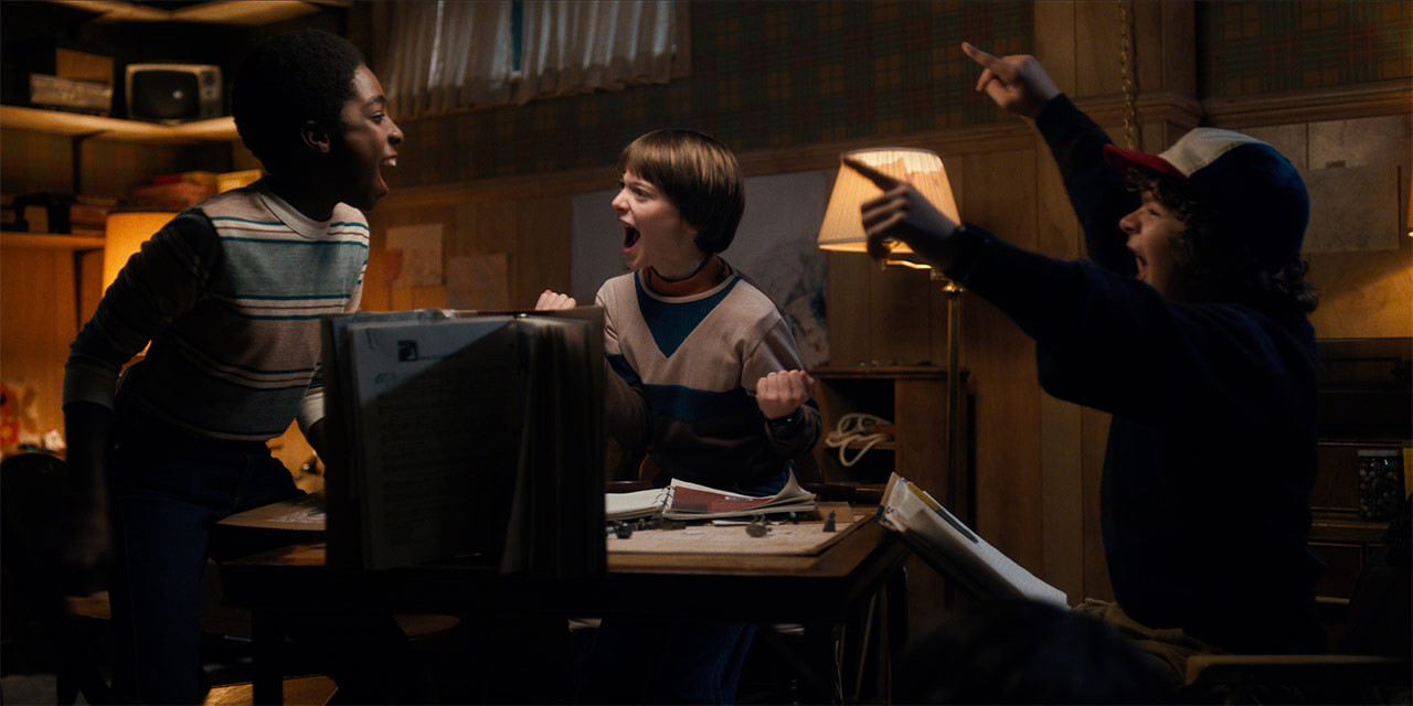 The boys from Stranger Things sit around a table in Mike's basement playing D&D